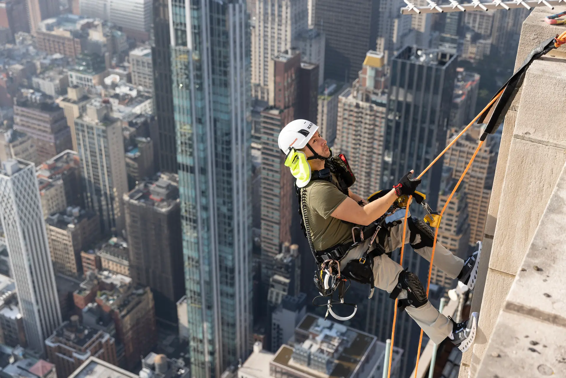 An engineer inspects the façade of a building on ropes.