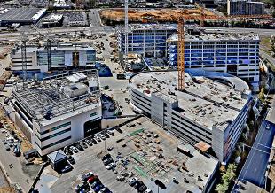 Both projects recently reached structural completion, marked by a joint topping-off celebration. The healthcare facilities are scheduled to open in 2028. 