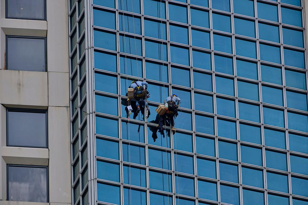 A group of workers cleaning windows via rope access.