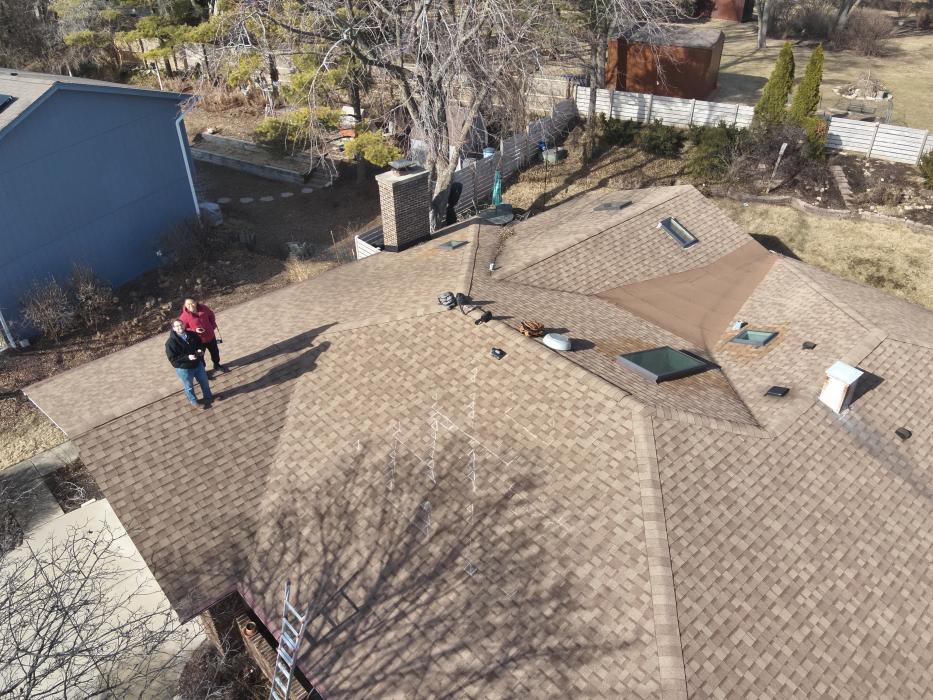 Drone view of asphalt shingle roof with hail impacts.