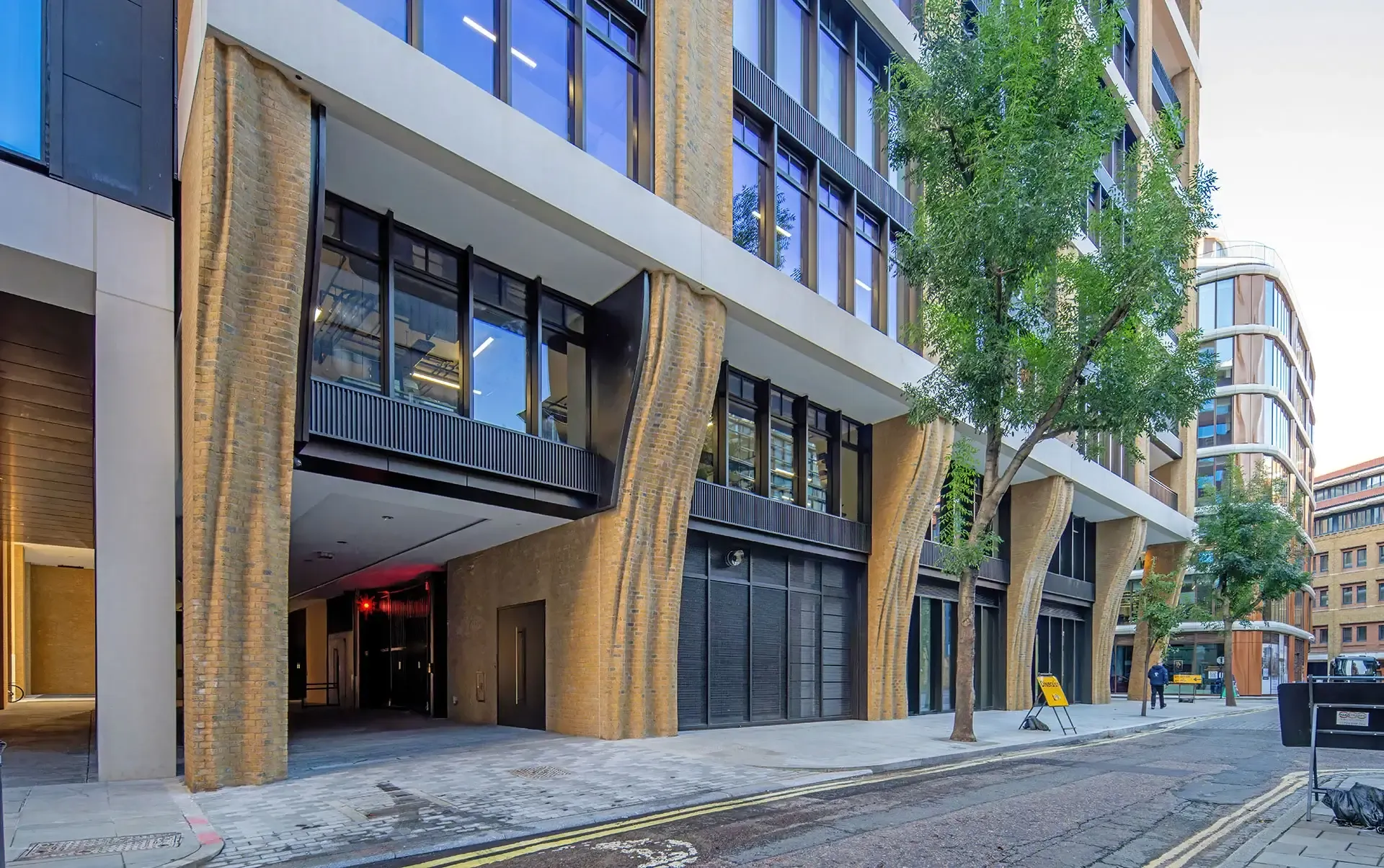 The building’s envelope combines brick-faced precast piers, reconstructed stone beams, and generous glazing to bring daylight deep into the floorplates. 